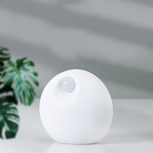 White spherical smart pet deodorizer with a sensor, designed for litter basins, shown against a light gray background with green leaves. - Image 2