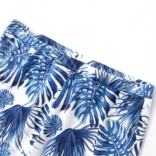 Family matching swimsuits with white and blue tropical leaf print, including men's shorts, women's and girl's ruffled one-shoulder bikinis. - Image 2
