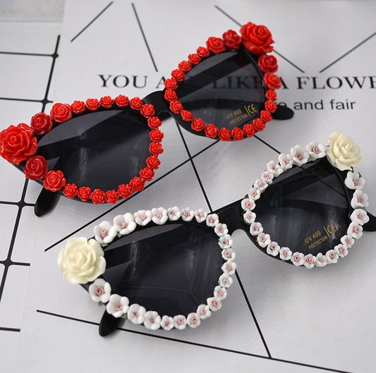 Black cat-eye sunglasses with dark lenses, adorned with small red rose embellishments along the frames. - Image 2