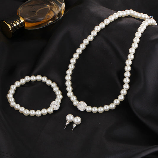 White pearl necklace, bracelet, and stud earrings set with pave crystal ball accents, displayed on a black stand. - Image 2