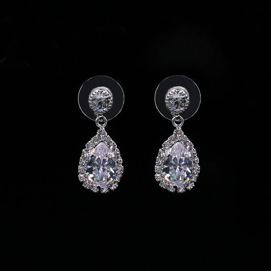 Sparkling silver-toned necklace and matching teardrop earrings set with clear stones, displayed on a black stand. - Image 2