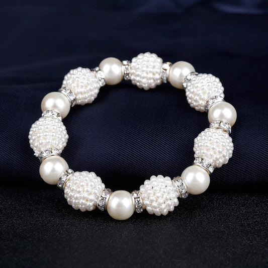 White faux pearl necklace, bracelet, and drop earrings set with rhinestone accents on a black display. - Image 2