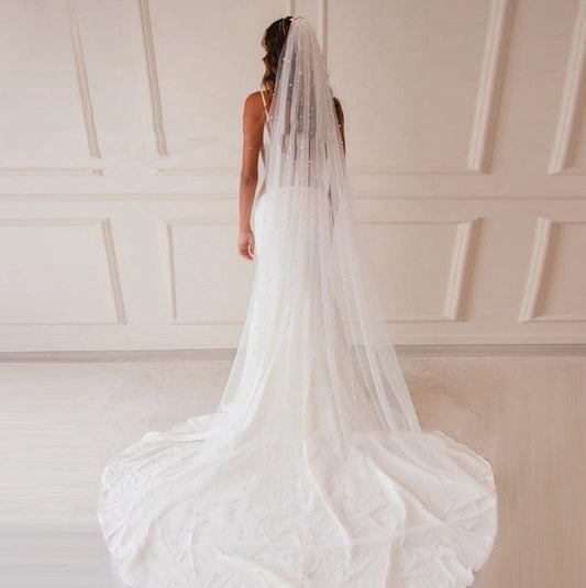 Mid-length white bridal veil with scattered pearl embellishments, flowing elegantly on a mannequin. - Image 2