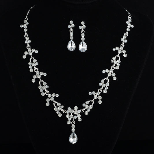 Silver-tone bridal jewelry set with a rhinestone floral necklace and matching teardrop dangle earrings on a black display. - Image 2