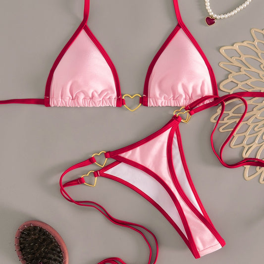 Pink and red halter-style triangle bikini with heart-shaped hardware and tie-up thong bottom, worn on a beach. - Image 2