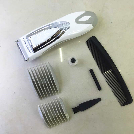 White and silver electric hair clipper held in hand, with a grey guide comb and blue packaging on a woven surface. - Image 2