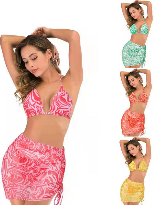 Women's three-piece swimsuit in red and orange abstract swirl print, featuring a halter bikini top, tie-side bottoms, and a ruched mini skirt. - Image 2