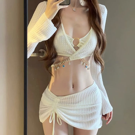 White three-piece bikini swimsuit set with a long-sleeve crop top, bikini top with gold ring, and ruched mini skirt. - Image 2