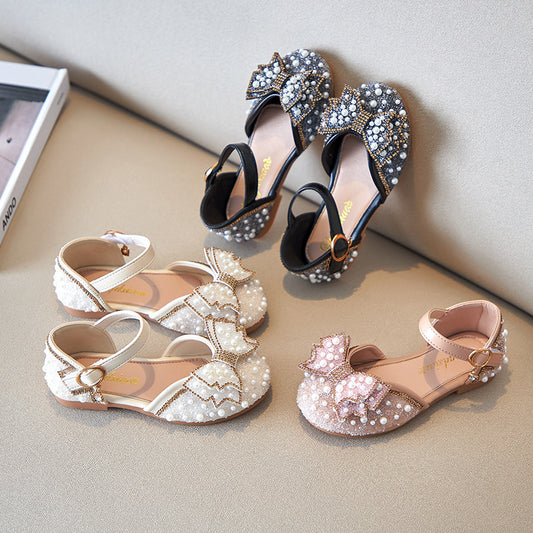 Beige girls' shallow mouth pumps with a large pink pearl bow, glitter, and an ankle strap with a gold buckle. - Image 2