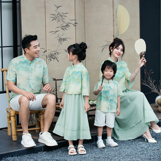 Mother and daughter in matching light green Chinese style cheongsam suits with patterned tops and solid skirts. - Image 2