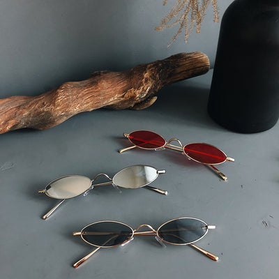 Silver-framed oval sunglasses with dark lenses reflecting a warm-toned object, displayed on a white tray. - Image 2