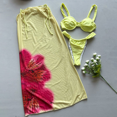 Woman in a light yellow three-piece bikini with an underwire top, matching bottoms, and a sheer floral sarong skirt. - Image 3