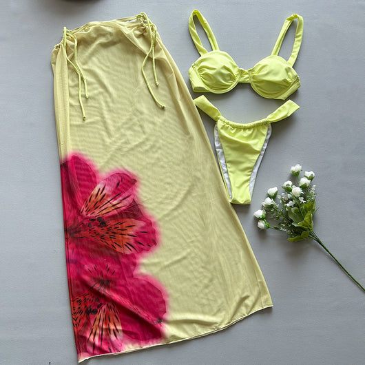 Woman in a light yellow three-piece bikini with an underwire top, matching bottoms, and a sheer floral sarong skirt. - Image 3