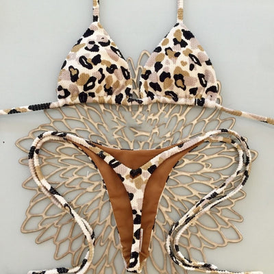 White textured bikini with red cherry print, featuring a triangle top and tie-side bottoms, on a woven mat. - Image 3