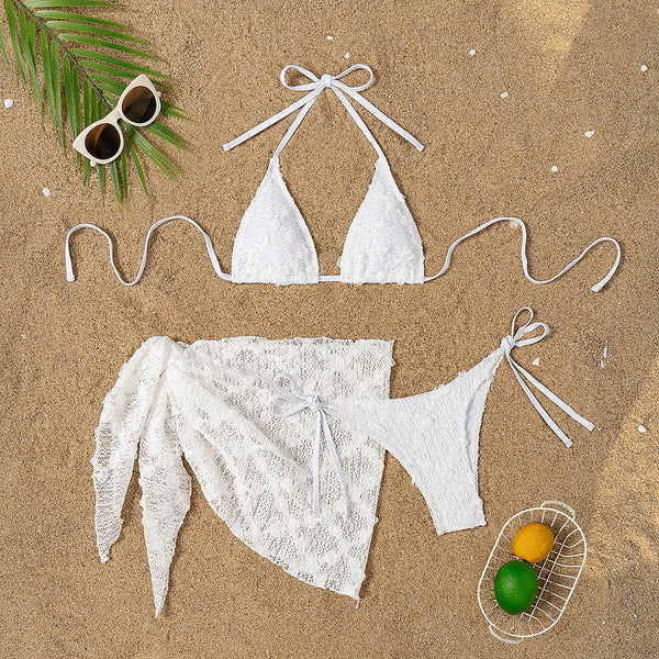 White lace halter bikini set with a matching mesh sarong, laid out on sand with sunglasses and a palm leaf. - Image 6