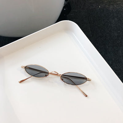 Silver-framed oval sunglasses with dark lenses reflecting a warm-toned object, displayed on a white tray. - Image 7