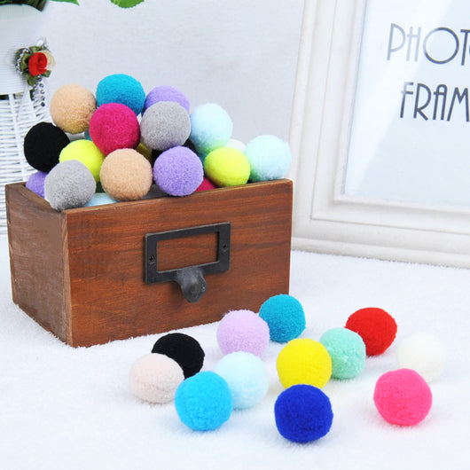 Assortment of colorful plush pom-pom balls, some in a wooden box, others scattered on a white surface. - Image 7