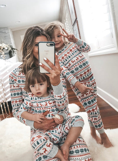 Family of four wearing matching white, red, and green fair isle Christmas pajamas with reindeer and snowflake patterns. - Image 13