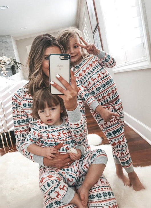 Family of four wearing matching white, red, and green fair isle Christmas pajamas with reindeer and snowflake patterns. - Image 13