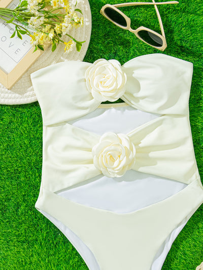White strapless one-piece swimsuit with 3D flower details and side cut-outs, worn by a woman by an infinity pool. - Image 4