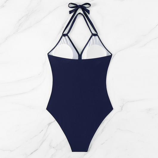 Woman in a green halter-neck one-piece swimsuit with cross-strap design and mesh cutouts, on a beach. - Image 19