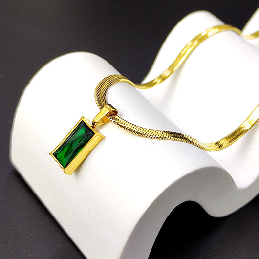 Gold hoop earrings with rectangular emerald green zircon pendants, displayed on a light beige fabric. - Image 4