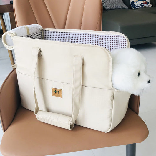 Two-tone beige and brown canvas pet carrier bag with mesh top and a small white dog peeking out.