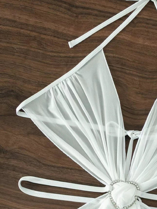 White three-piece halter neck bikini and sheer cover-up set with a heart-shaped embellishment, laid flat on wood. - Image 15
