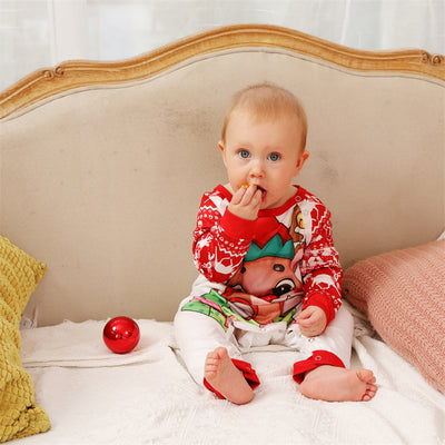 Baby wearing a red and white Christmas pajama set with a fawn graphic, sitting on a white blanket. - Image 7