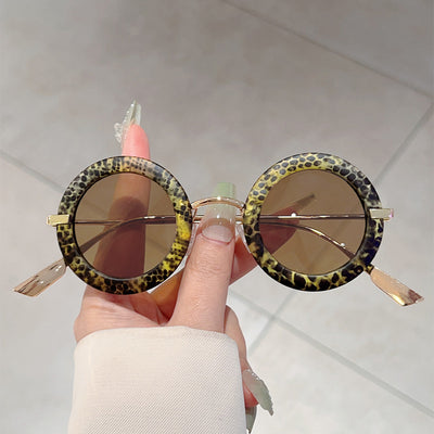 Small frame oval fashion sunglasses with black frames and vibrant orange lenses, held by a hand. - Image 7