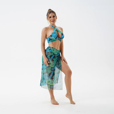Women's plus size split swimsuit with a blue and green tropical leaf print halter bikini top and matching sarong skirt.