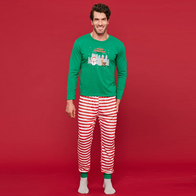 Child wearing green Christmas pajamas with a giraffe graphic and red striped pants, next to a flocked tree. - Image 4