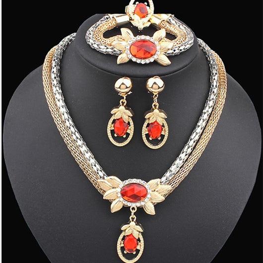 Bridal four-piece jewelry set with gold and silver-tone necklace, earrings, bracelet, and ring, featuring red crystal flowers.