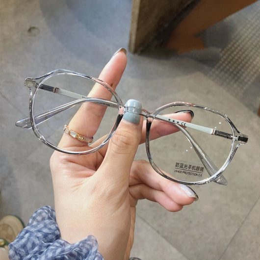 Transparent blue anti-blue light glasses with a vintage round frame and clear lenses, held by a hand. - Image 4