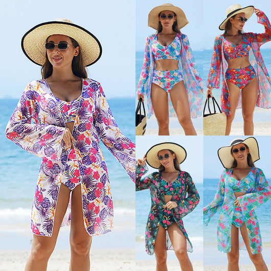 Multicolor tropical print three-piece swimsuit set with high-waisted bikini and sheer mesh cover-up on a beach.