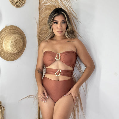 Red one-piece swimsuit with a strapless bandeau top, midriff cut-outs, and two gold-tone buckle details. Features a high-cut bottom.