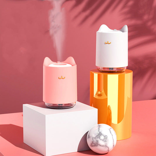 White mini USB humidifier with cat ears and a gold cat nose/mouth emblem, featuring a clear water tank base.