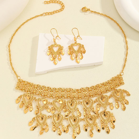 Gold heart-shaped hollow necklace and matching dangle earrings set on a woman wearing a black top. - Image 3