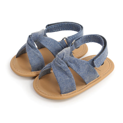 Black baby sandals with knotted cross straps and a matching black floral headband on a white background. - Image 35