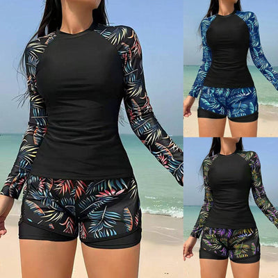 Women's long-sleeve tankini swimsuit with black top and blue tropical leaf print raglan sleeves, matching swim shorts.