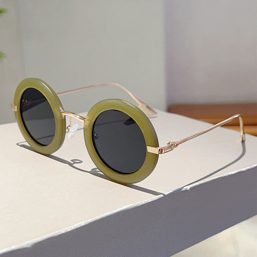 Small frame oval fashion sunglasses with black frames and vibrant orange lenses, held by a hand. - Image 17