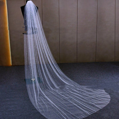 Mid-length white bridal veil with scattered pearl embellishments, flowing elegantly on a mannequin. - Image 6