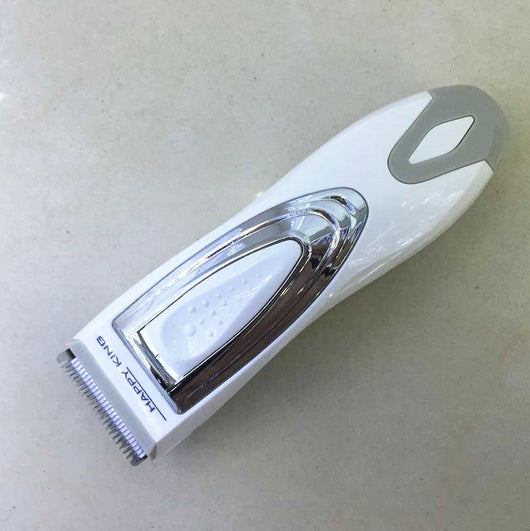 White and silver electric hair clipper held in hand, with a grey guide comb and blue packaging on a woven surface. - Image 8