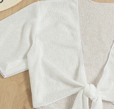 White two-piece swimwear set with a tie-front crop top and a high-waisted skirt with an asymmetrical ruffled hem. - Image 13