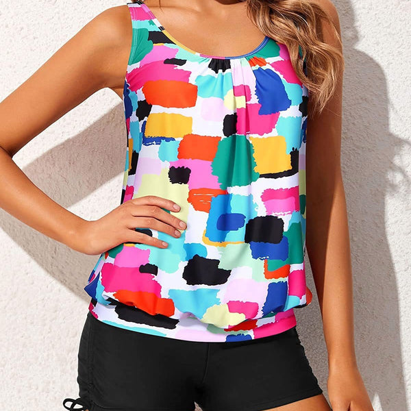 Women's two-piece tankini swimsuit with a colorful abstract print tank top and solid black ruched swim shorts.