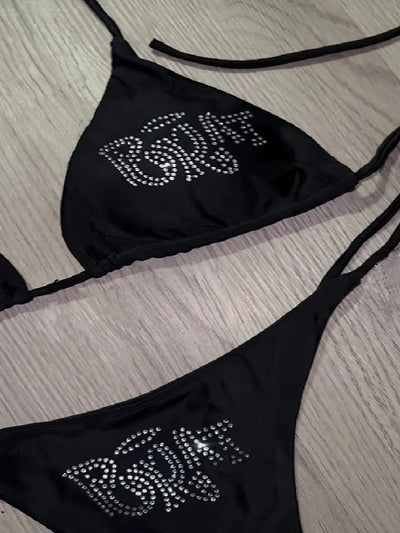 Black halter bikini with rhinestone 'BRAT' lettering on triangle top and tie-side bottom, displayed on white faux fur. - Image 14