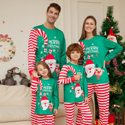 Family of four wearing matching green Christmas pajamas with Santa, reindeer, and red striped pants.