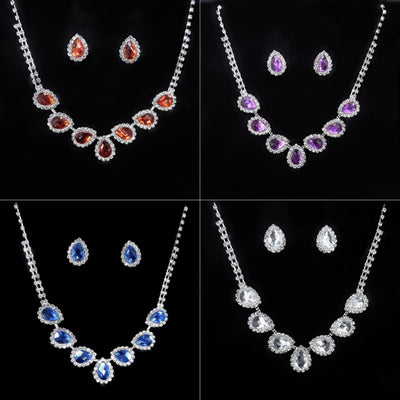 Purple teardrop rhinestone necklace and matching stud earrings set on a black background.