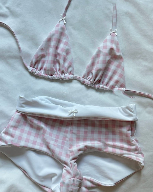 Red and white gingham high-waisted bikini set with triangle top, laid on sand under sunlight. - Image 9