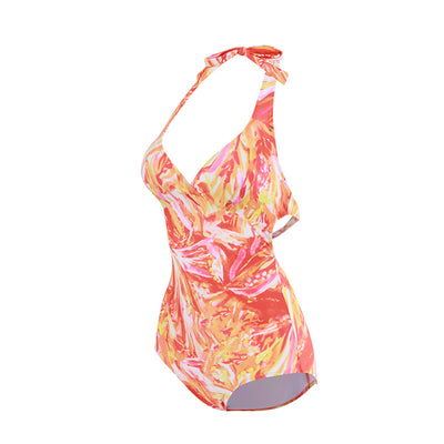 Woman in an orange and pink patterned halter neck backless cover-up dress with a straw hat on a sandy beach. - Image 5
